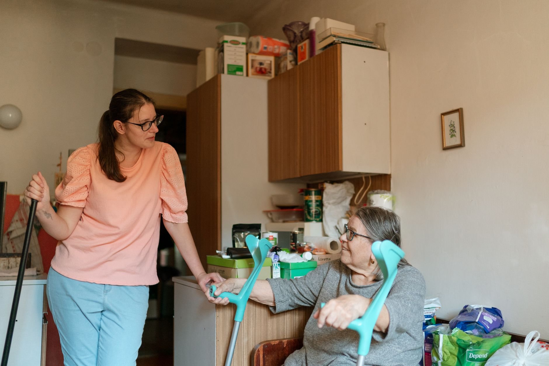 A caregiver engaging with a senior using crutches in a cozy home environment.